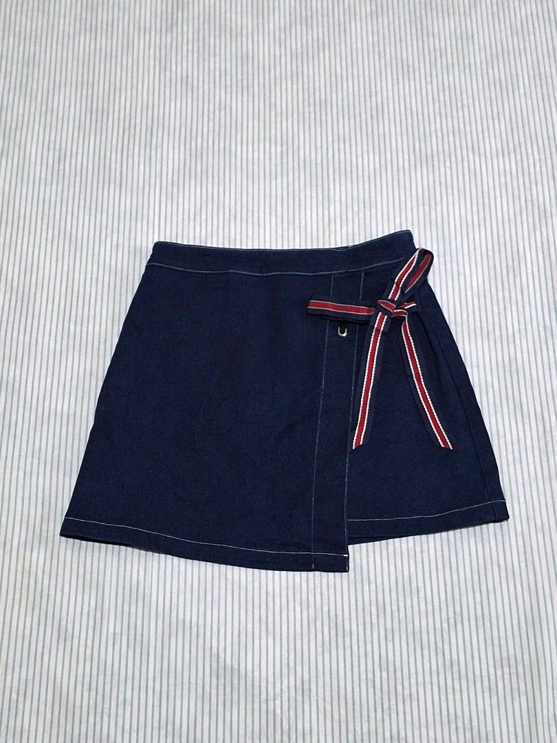Vero Moda Denim Wrap Skirt Size M (Category: Skirts) located in Taguig. Submitted by butterflypea.thrift (Listing ID 1462852599, Image 1). Description: - Vero Moda dark wash denim wrap skirt - Size: waist - 28 , length - 15 - Features a side tie detail - Red and blue stripe accent on tie - Material: Cotton with stretch - Ideal for casual outfits.