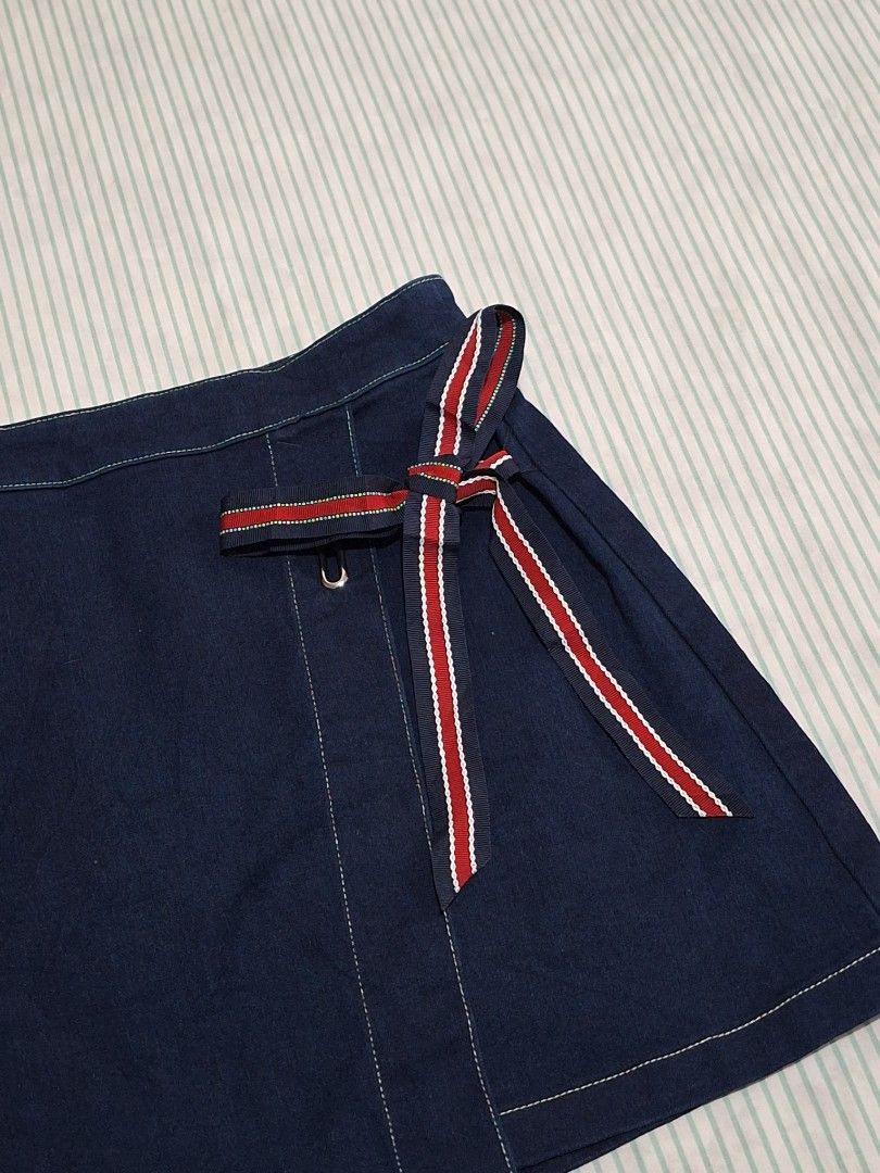Vero Moda Denim Wrap Skirt Size M (Category: Skirts) located in Taguig. Submitted by butterflypea.thrift (Listing ID 1462852599, Image 2). Description: - Vero Moda dark wash denim wrap skirt - Size: waist - 28 , length - 15 - Features a side tie detail - Red and blue stripe accent on tie - Material: Cotton with stretch - Ideal for casual outfits.