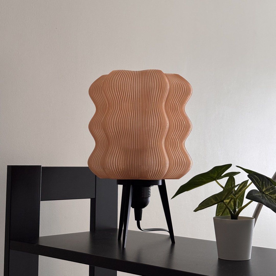 Brown Wavy Lamp (with Ikea LED bulb) (Category: Lighting) located in Mandaluyong City. Submitted by taag_ (Listing ID 1462877599, Image 3). Description: - Brand new, comes in a box and paper bag - Translucent light brown - 18cm L x 18 cm W x 28 cm H - 3D printed, please allow minimal imperfections - Comes with an Ikea E27 Solhetta LED bulb (warm light) Licensed design by Eris https://makerworld.com/@eris2000.
