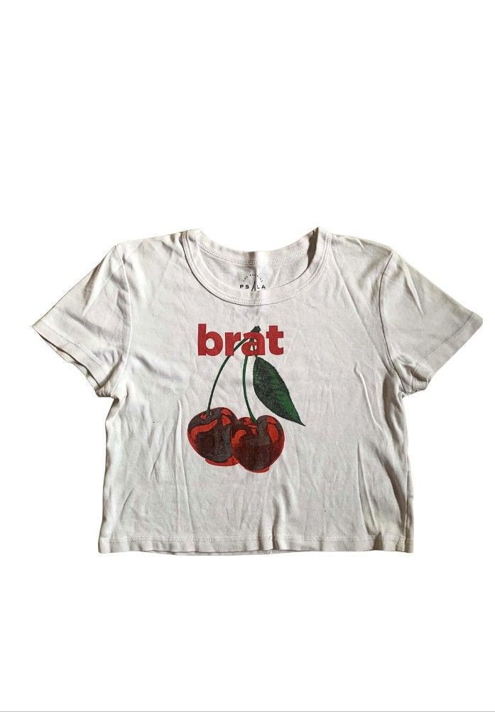White 'Brat' Cherry Graphic Crop Top (Category: Shirts) located in Tiaong. Submitted by cdoswan (Listing ID 1461569938, Image 1). Description: - White cropped t-shirt - Features a red 'brat' graphic with two cherries - Short sleeves and crew neck - Ideal for casual wear.