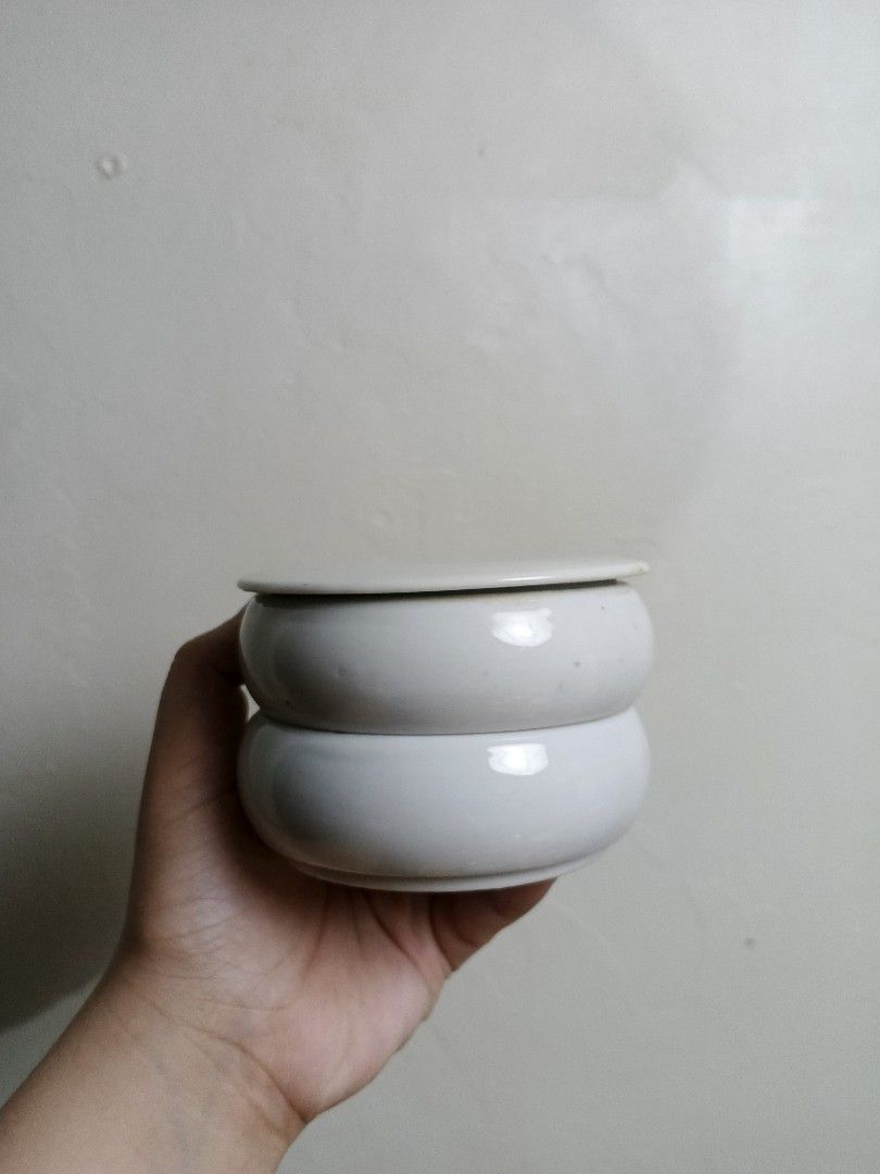 White ceramic lidded container pot (Category: Food Organization & Storage) located in Quezon City. Submitted by pawenn (Listing ID 1462853984, Image 1). Description: - Chic white ceramic pot with a convenient lid. - Stackable design for space-saving storage. - Ideal for organizing small essentials on your desk or vanity. - Features a clean and simple aesthetic. - Dimensions: Approximately X cm (height) x Y cm (width)..