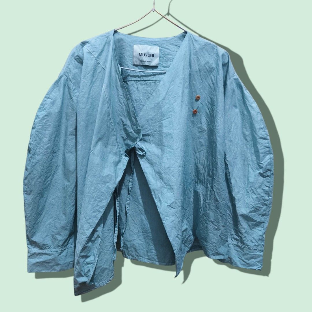 Wrap style blouse light aqua green (Category: Shirts) located in Taguig. Submitted by deyerreC2020 (Listing ID 1462854698, Image 2). Description: sale tops MUYUDI old green wrap shirt with asymmetrical wooden button closure. cotton fabric, long sleeves, wrap style tie inside adjustable to XL bust size Perfect for casual or layered outfits. MOP:gcash/Maya/cash.