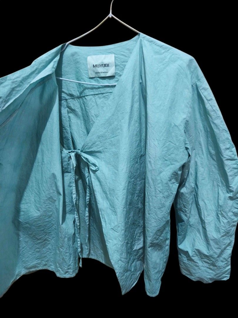 Wrap style blouse light aqua green (Category: Shirts) located in Taguig. Submitted by deyerreC2020 (Listing ID 1462854698, Image 3). Description: sale tops MUYUDI old green wrap shirt with asymmetrical wooden button closure. cotton fabric, long sleeves, wrap style tie inside adjustable to XL bust size Perfect for casual or layered outfits. MOP:gcash/Maya/cash.