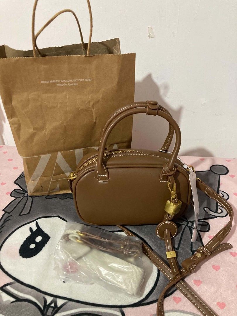 Zara Brown Mini Barrel Bag with Strap (Category: Shoulder Bags) located in Binan City. Submitted by leiramanailla (Listing ID 1462795458, Image 1). Description: - Cute brown mini barrel bag from Zara - Features a top handle - Detachable crossbody strap included - Comes with a charming gold cube accent - Original Zara paper bag included - Ideal size for carrying your essentials.