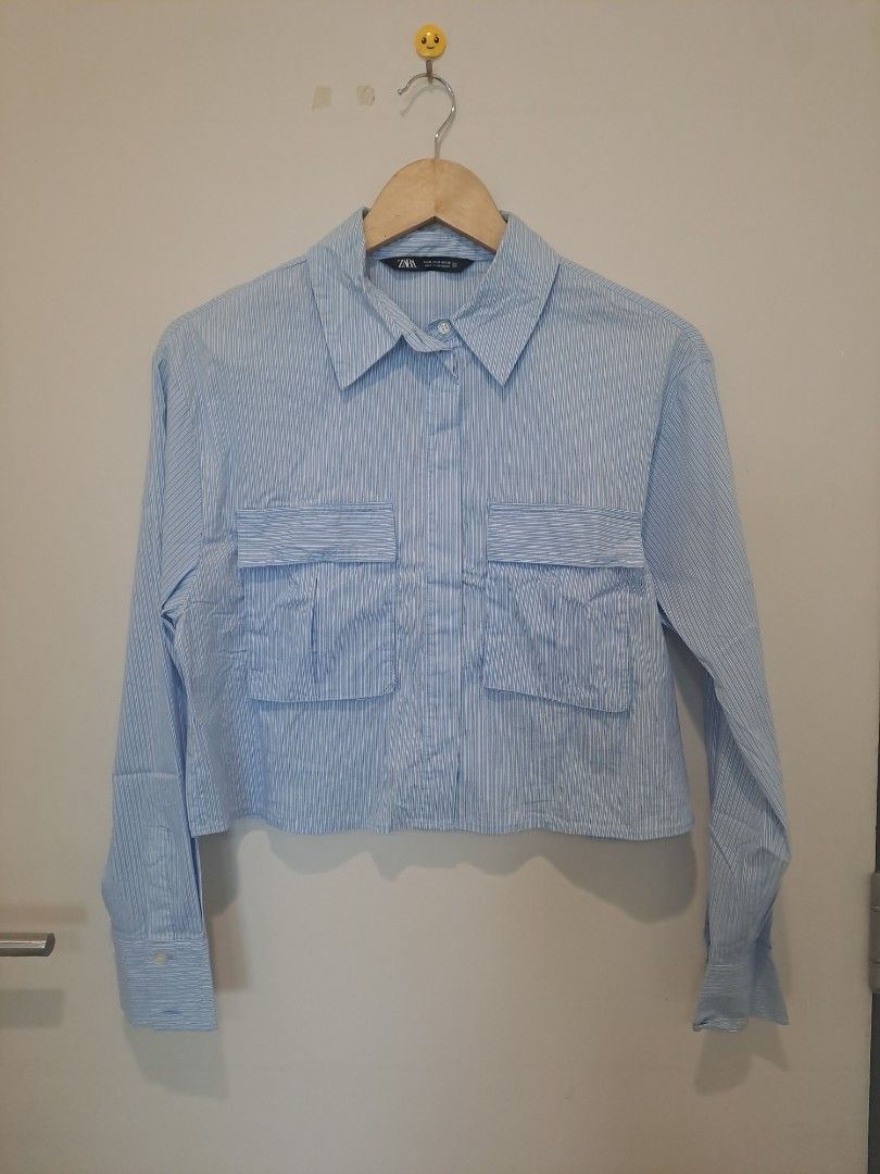 Zara Crop blue pinstripes (Category: Longsleeves) located in Manila. Submitted by joanbalde39643 (Listing ID 1462778571, Image 1). Description: This is a Zara light blue and white striped cropped shirt, characterized by its boxy silhouette, structured collar, and twin oversized front patch pockets. Made from lightweight cotton or poplin blend fabric, it features long sleeves with buttoned cuffs and a clean button-down front placket..