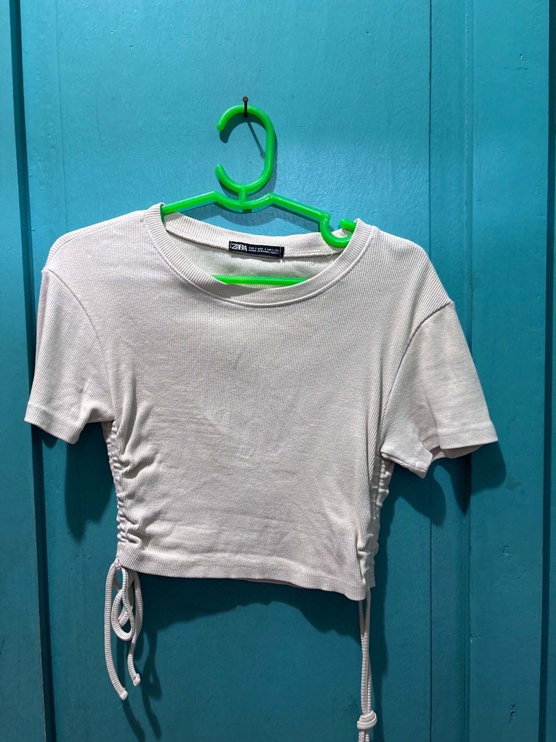 Zara Ribbed Ruched Crop Top (Category: Sleeveless) located in Cabuyao City. Submitted by dumbonita (Listing ID 1462836819, Image 1). Description: - Cream ribbed crop top from Zara - Adjustable ruched sides with drawstring ties - Short sleeves and crew neck - Versatile for casual or dressed-up outfits.
