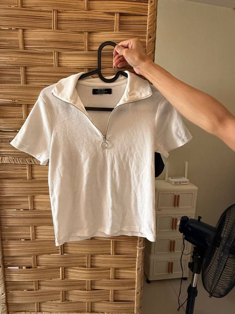 Bershka White Collared Zip Up Cropped Top (Category: Blouses) located in Manila. Submitted by jimmy_juniorrr (Listing ID 1459177841, Image 1). Description: - White Bershka cropped top - Short sleeves - Collared neckline - Zip-up front - Textured fabric - Versatile: pairs well with high-waisted jeans or skirts - Suitable for casual or dressed-up looks.