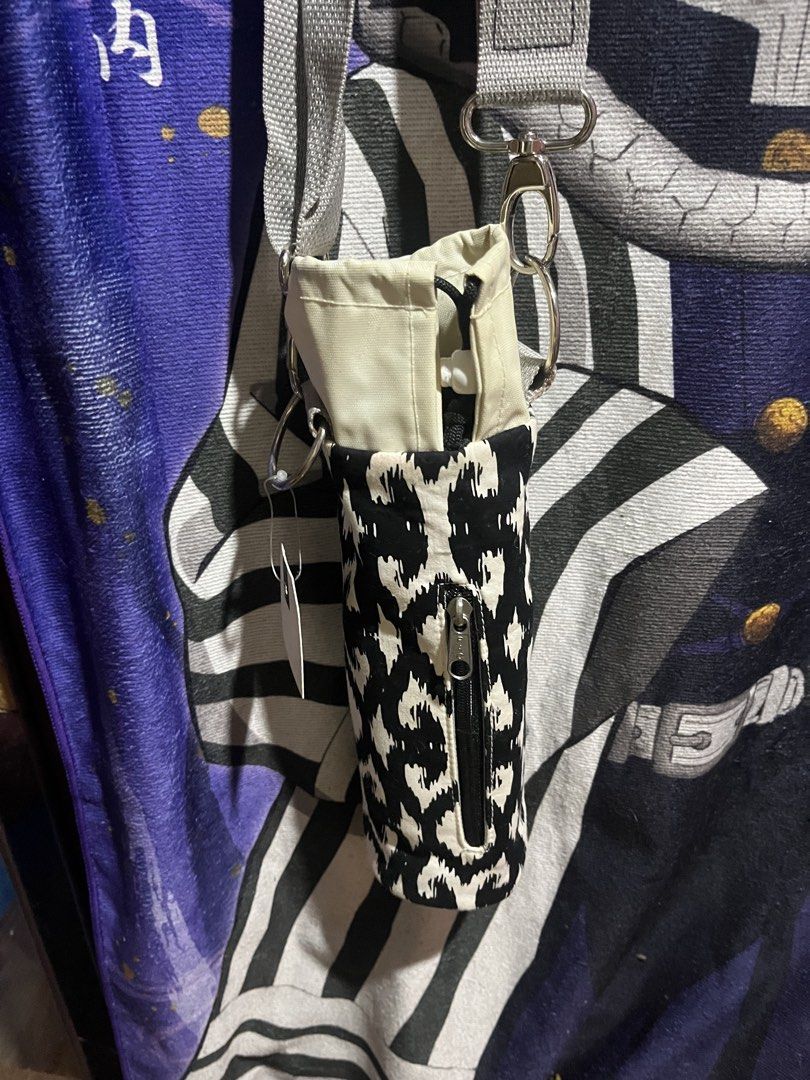 Black and White Patterned Bottle Holder Bag with Strap (Category: Cross-body Bags) located in Manila. Submitted by schwarzer0 (Listing ID 1459149767, Image 2). Description: - Stylish black and white geometric pattern bottle holder. - Features a convenient small zippered pocket on the front. - Includes an adjustable grey strap for comfortable carrying. - Ideal for keeping your water bottle accessible during daily activities or outdoor adventures. 
