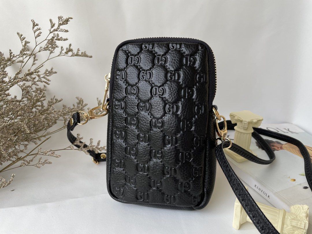 Black Embossed GD Phone Pouch Bag with Strap (Category: Purses & Pouches) located in Taguig. Submitted by ilovetradra (Listing ID 1459094395, Image 1). Description: - Chic black phone pouch - Features embossed GD pattern - Secure top zipper closure - Detachable strap for versatile wear (crossbody or clutch) - Elegant gold hardware details - Plain textured finish on the back - Ideal for carrying your phone and daily essentials.