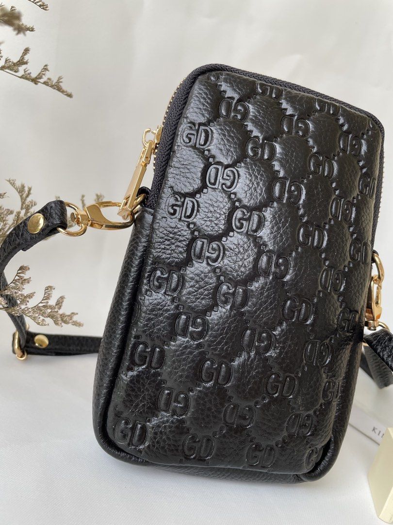 Black Embossed GD Phone Pouch Bag with Strap (Category: Purses & Pouches) located in Taguig. Submitted by ilovetradra (Listing ID 1459094395, Image 3). Description: - Chic black phone pouch - Features embossed GD pattern - Secure top zipper closure - Detachable strap for versatile wear (crossbody or clutch) - Elegant gold hardware details - Plain textured finish on the back - Ideal for carrying your phone and daily essentials.