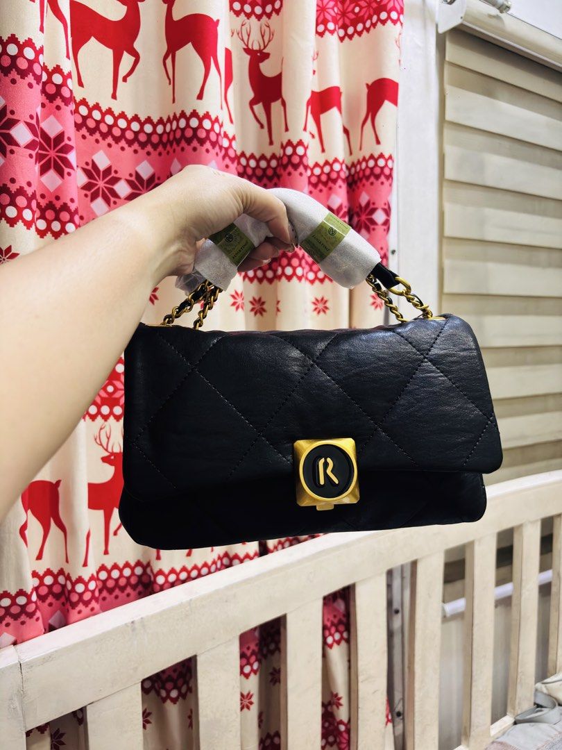 Black Quilted Handbag with Gold 'R' Clasp (Category: Luxury Bags & Wallets) located in Quezon City. Submitted by itsmeriaa (Listing ID 1459248744, Image 1). Description: - Stylish black quilted handbag - Features a gold clasp with an 'R' logo - Elegant chain strap detail - Handles still in original protective packaging - Ideal for everyday use.