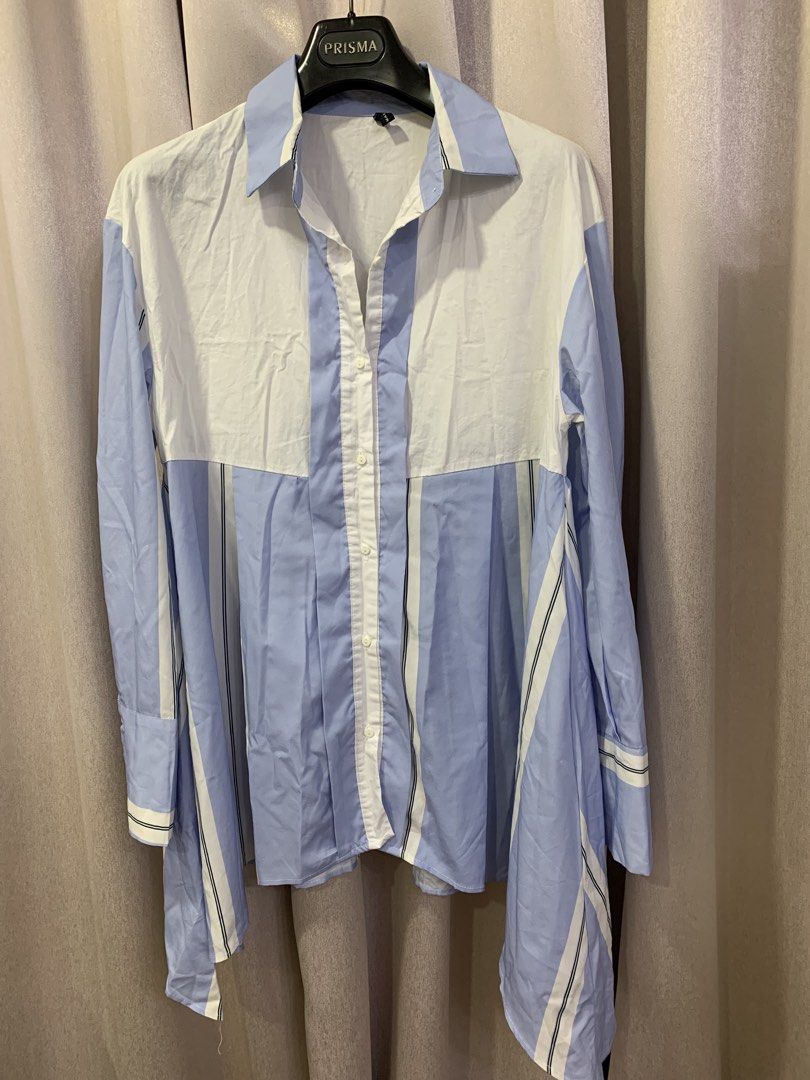 Blue and White Striped Asymmetrical Button-Up Shirt (Category: Shirts) located in Pasig City. Submitted by angelamendozaaa (Listing ID 1459134479, Image 1). Description: - Cool blue and white vertical stripes - Asymmetrical hemline for a modern look - Classic button-up front and collar - Long sleeves with button cuffs - Unique pleated detail on the front - Versatile for casual or smart-casual outfits.