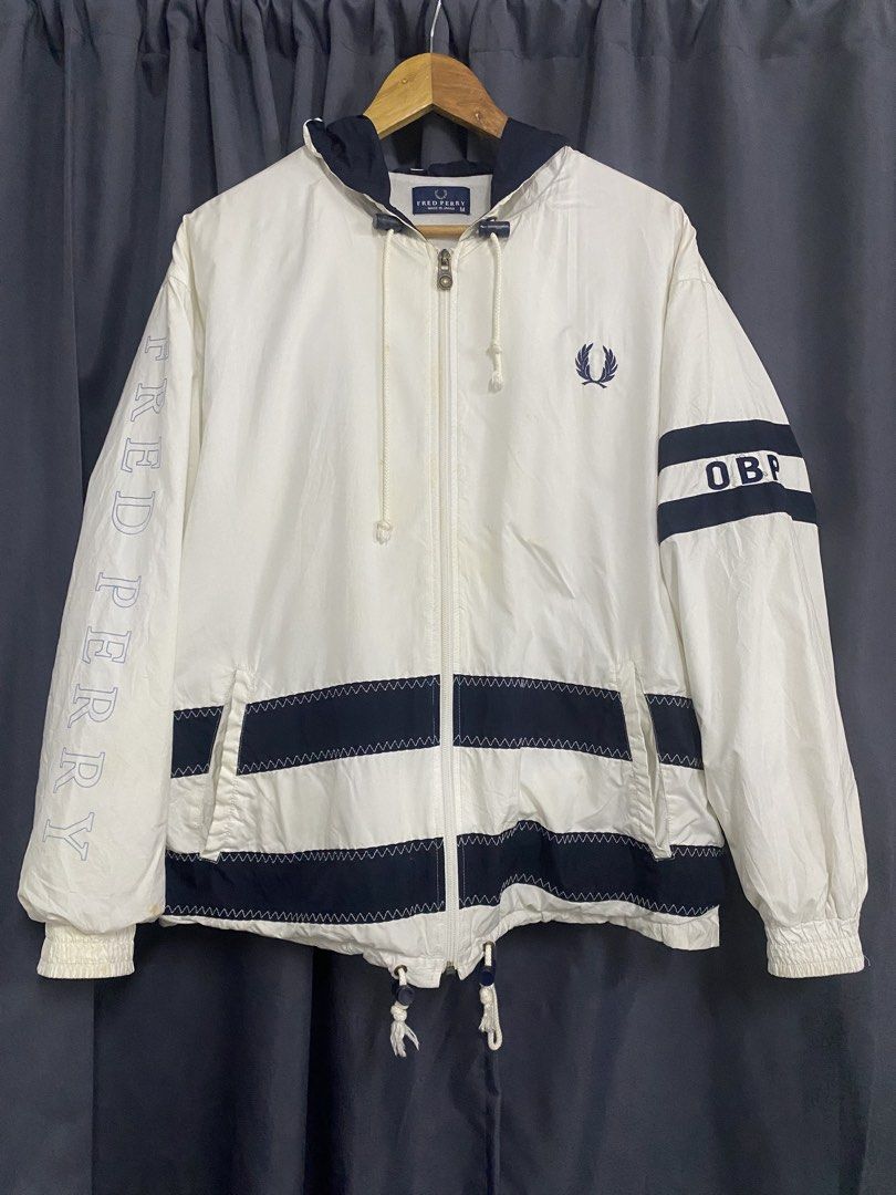Fred Perry x Panasonic Windbreaker Jacket (Category: Coats, Jackets and Outerwear) located in Santa Maria. Submitted by saintarchive316 (Listing ID 1459192753, Image 1). Description: - White windbreaker jacket with navy blue accents - Features the iconic Fred Perry laurel wreath logo on the front - 'Panasonic' logo prominently displayed on the back - 'FRED PERRY' text printed on the left sleeve - Adjustable drawstring hem and hood for a customize