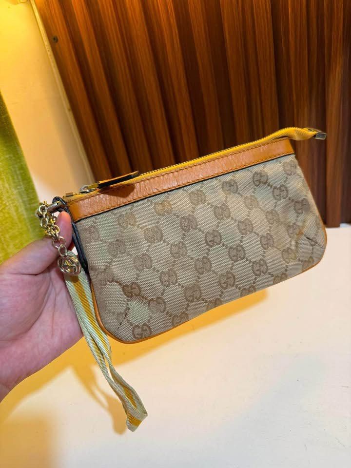 Gucci GG Monogram Canvas Pouch Wristlet (Category: Luxury Bags & Wallets) located in Los Banos. Submitted by ukaynidizkie (Listing ID 1459215034, Image 1). Description: - Gucci pouch - Classic GG monogram canvas - Tan and orange leather trim - Includes wrist strap - Features chain detail - Secure zipper closure - Ideal for carrying your essentials.