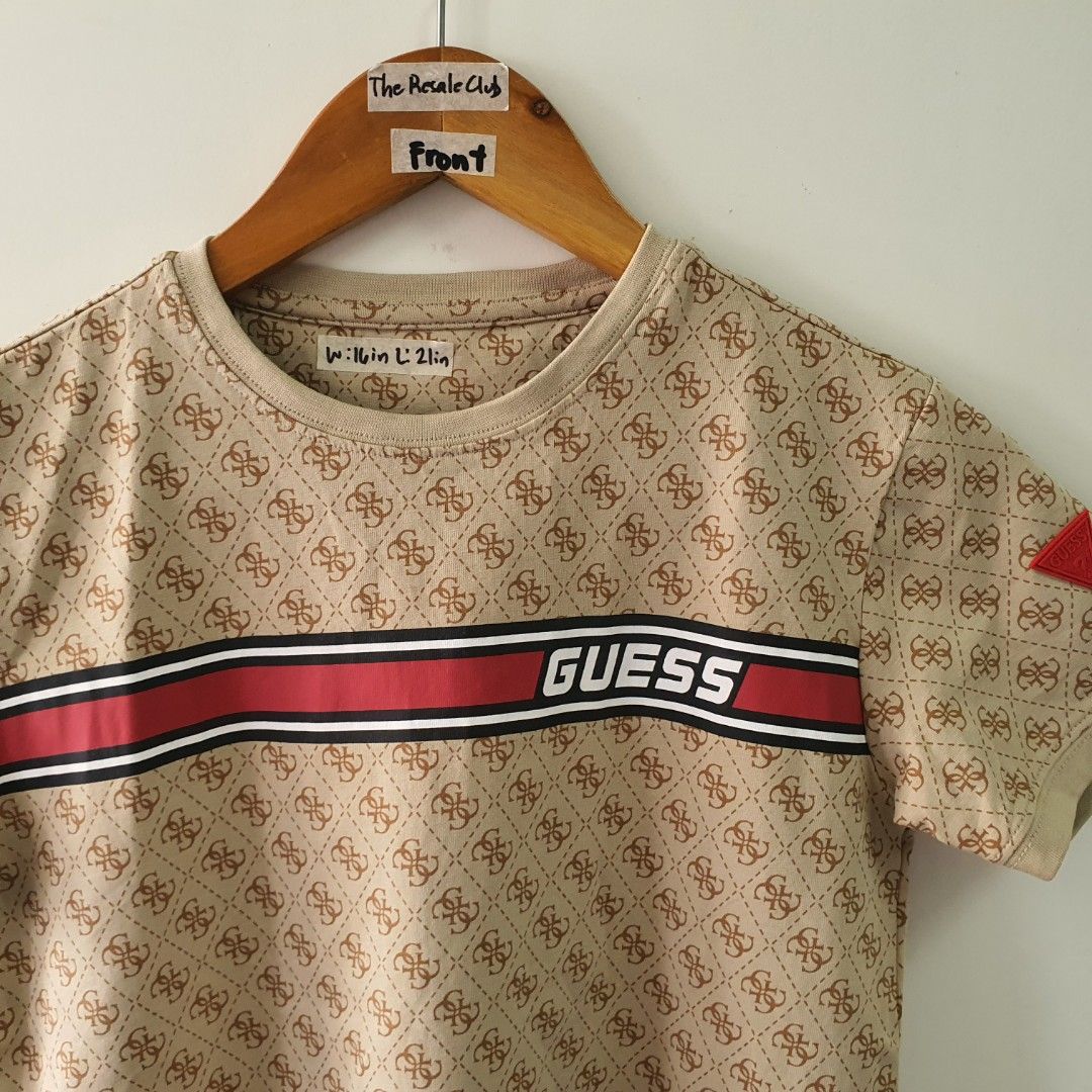 Guess All Over Print T-Shirt (Category: Babies & Kids Fashion) located in Tarlac. Submitted by resaleclub (Listing ID 1459260763, Image 2). Description: - Tan Guess t-shirt - Size: L - All-over monogram print - Classic Guess logo on chest with red and white stripes - Small red Guess triangle logo on sleeve - Ideal for casual wear.