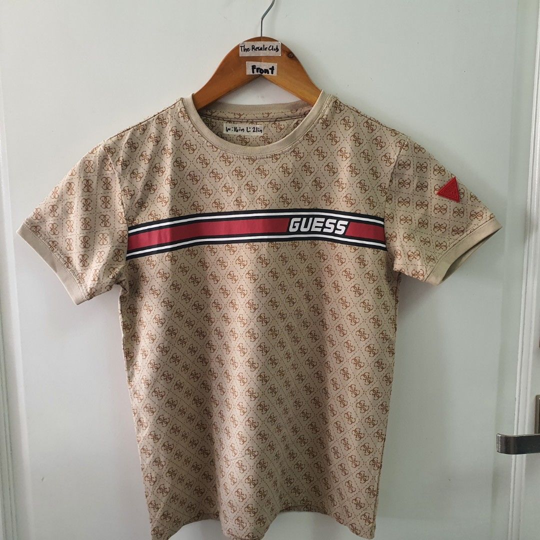 Guess All Over Print T-Shirt (Category: Babies & Kids Fashion) located in Tarlac. Submitted by resaleclub (Listing ID 1459260763, Image 1). Description: - Tan Guess t-shirt - Size: L - All-over monogram print - Classic Guess logo on chest with red and white stripes - Small red Guess triangle logo on sleeve - Ideal for casual wear.