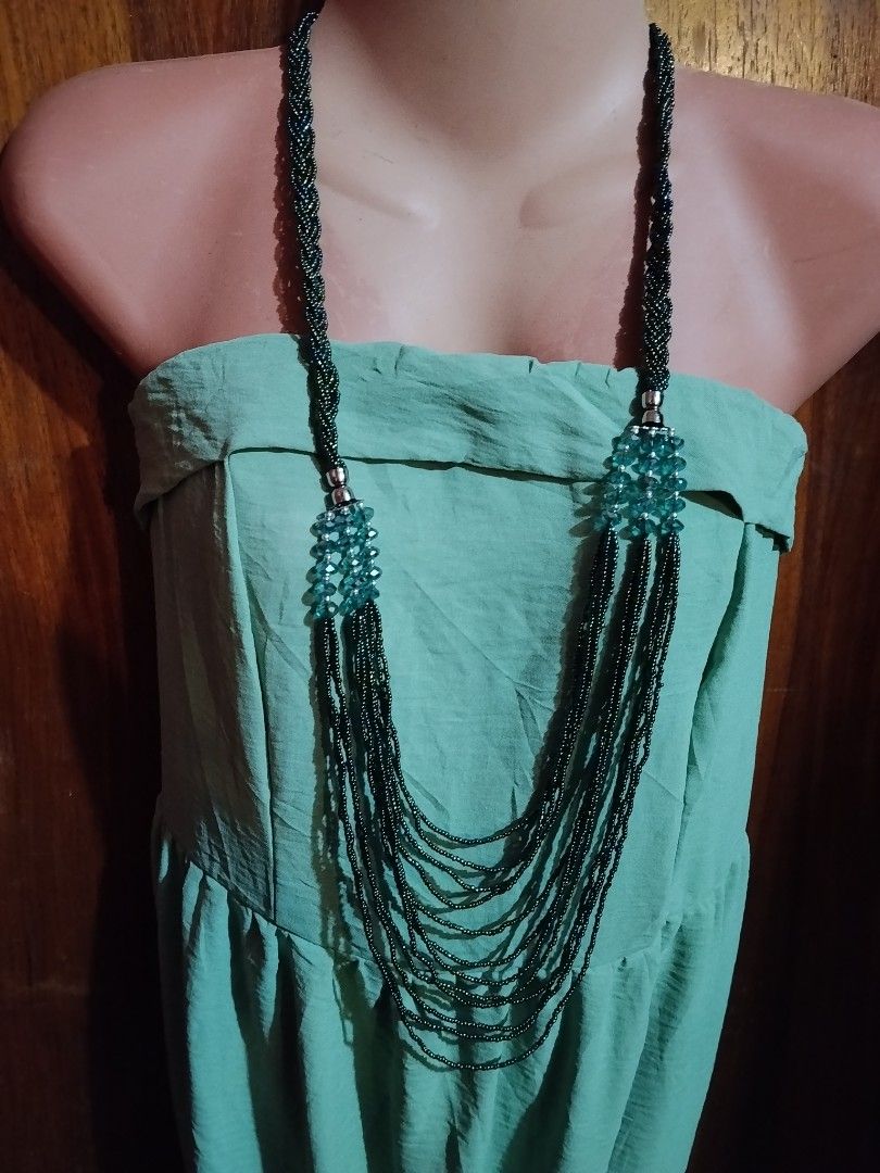 Multi-strand beaded necklace with blue crystal accents (Category: Necklaces) located in Las Pinas. Submitted by budgetbuddies (Listing ID 1459201316, Image 3). Description: - Long beaded necklace - Features braided strands on the sides - Multiple dark green strands cascade down - Accented with clear blue crystal beads - Unique layered design - Perfect statement piece.