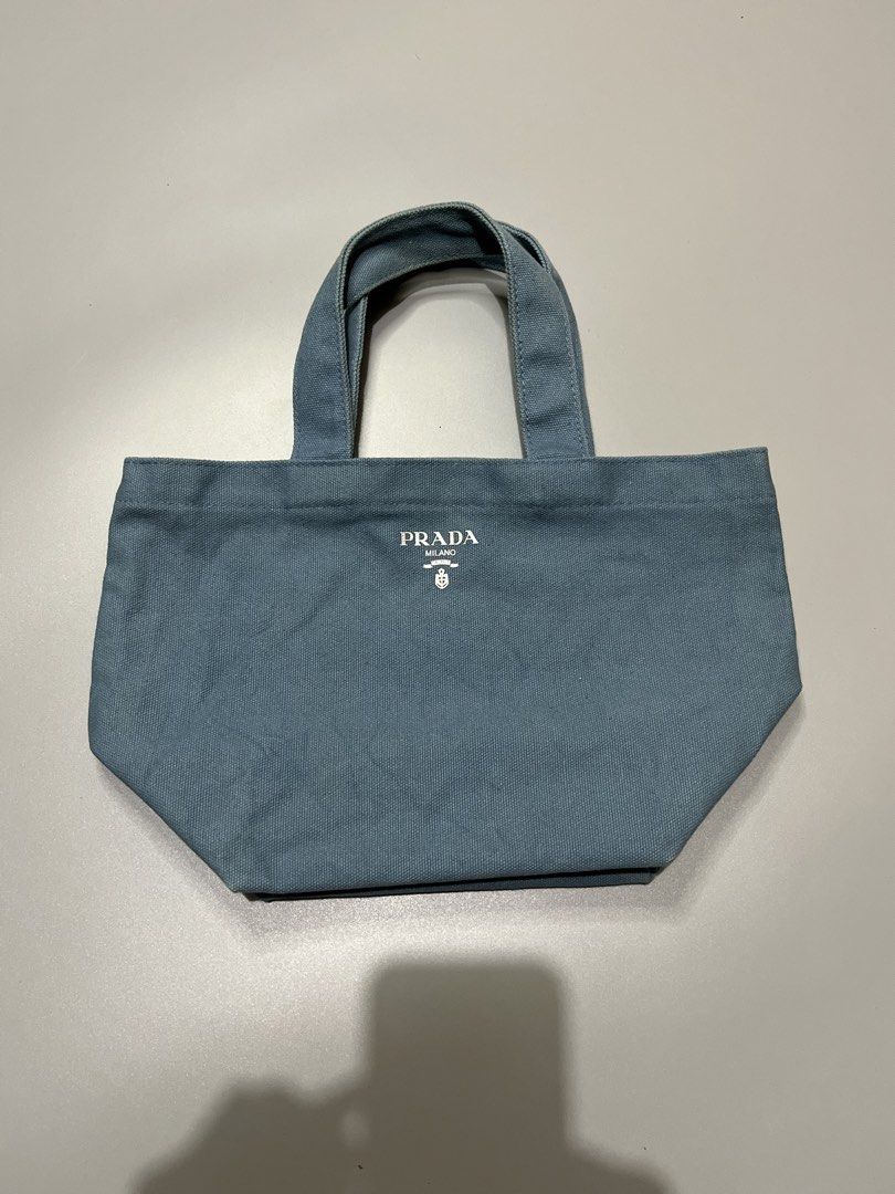 Prada Canvas Tote Bag (Category: Luxury Bags & Wallets) located in Manila. Submitted by jorgemabelin2001 (Listing ID 1459108449, Image 2). Description: - Light blue Prada canvas tote bag - Simple and classic design, perfect for everyday use - Features sturdy handles for durability - Iconic Prada logo printed on the front - Compact size, ideal for carrying your essentials.
