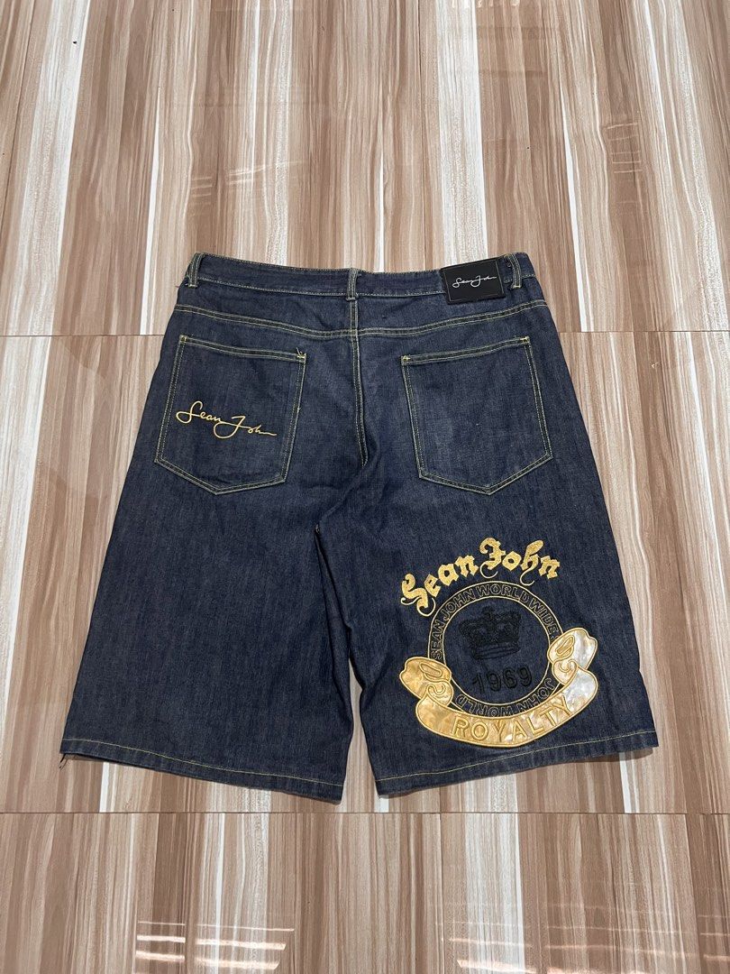 Sean John Denim Shorts - Size 36 (Category: Shorts) located in San Pablo. Submitted by jilescalla (Listing ID 1459130340, Image 2). Description: - Brand: Sean John - Style: Dark Wash Denim Shorts - Size: 36 - Features: Signature embroidered logo on back pocket - Graphic: Large embroidered graphic on right leg with 'Sean John', '1969', 'Royalty', 'Sean John Worldwide' - Closure: Button and zip fly - Pockets: Classic five-pocket styling.