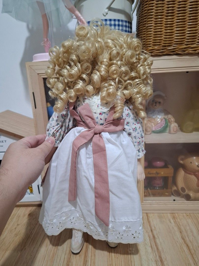 Vintage Porcelain Doll (Category: Dresses) located in Subic. Submitted by dailynicole (Listing ID 1459257032, Image 3). Description: - Beautiful porcelain doll - Long blonde curly hair - Floral print blouse - Pink pinafore dress with white lace trim - Bright blue eyes - Pink ribbon tie at the back of the dress - Ideal decorative piece - Great for collectors or as a gift.
