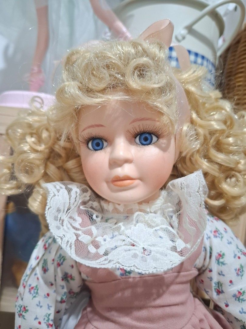 Vintage Porcelain Doll (Category: Dresses) located in Subic. Submitted by dailynicole (Listing ID 1459257032, Image 2). Description: - Beautiful porcelain doll - Long blonde curly hair - Floral print blouse - Pink pinafore dress with white lace trim - Bright blue eyes - Pink ribbon tie at the back of the dress - Ideal decorative piece - Great for collectors or as a gift.