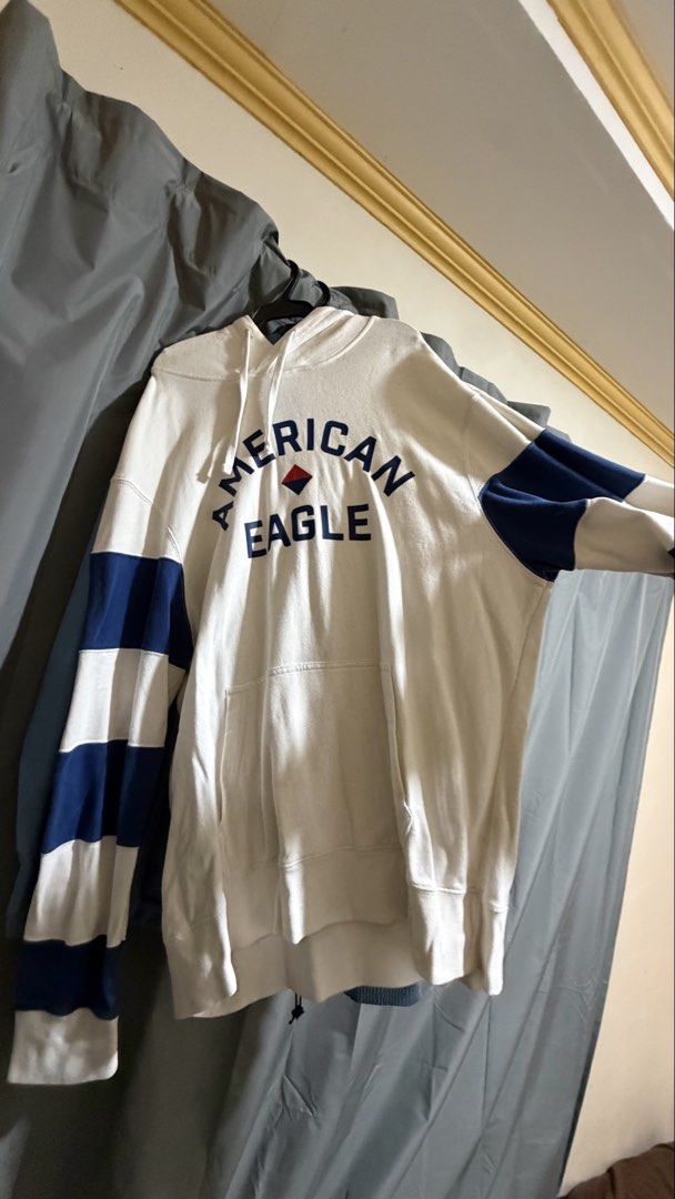 American Eagle White Hoodie with Blue Stripes (Category: Coats, Jackets and Outerwear) located in Manila. Submitted by sneakspxxks (Listing ID 1463028758, Image 1). Description: - White hoodie from American Eagle - Blue stripes on sleeves - "American Eagle" brand name across chest - Front pocket - Drawstring hood - Ideal for casual wear.