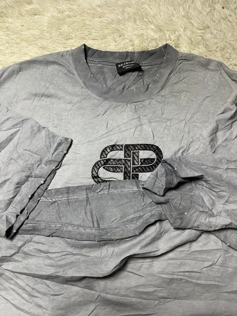 Balenciaga BB Interlock Logo Distressed T-shirt (Category: Tshirts & Polo Shirts ) located in Matanao. Submitted by jikeserran00389 (Listing ID 1462922713, Image 3). Description: This is a grey Balenciaga BB Interlock Logo T-shirt featuring a distressed crewneck and a textured black logo graphic across the chest. 23x30 Excellent Condition Complete tags.