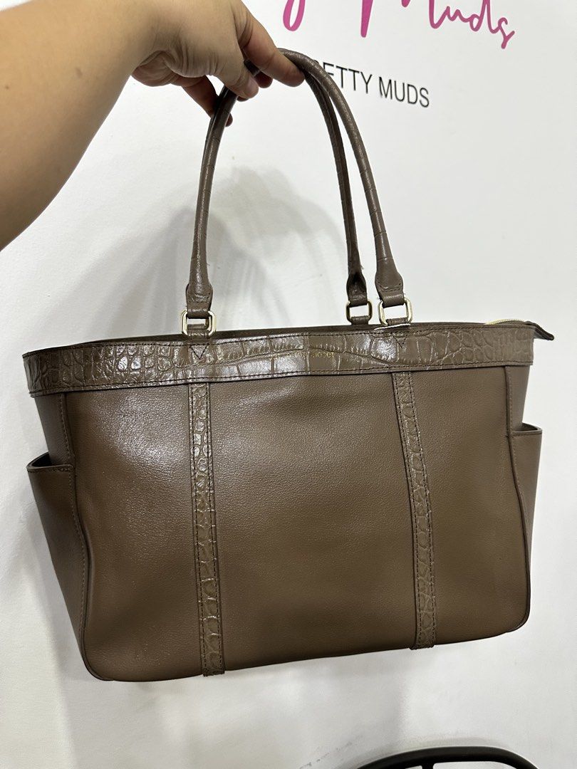 Brown Leather Tote Bag with Crocodile Trim (Category: Tote Bags) located in Cardona. Submitted by jaxdelossa10453 (Listing ID 1463012462, Image 1). Description: - Classic brown leather tote bag - Crocodile embossed trim on top and sides - Two convenient exterior pockets - Vibrant red fabric interior lining - Secure zipper closure with gold-tone pull - Spacious for daily essentials - Ideal for work or casual use.