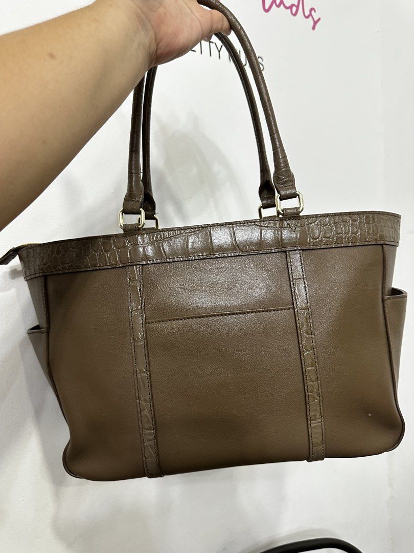 Brown Leather Tote Bag with Crocodile Trim (Category: Tote Bags) located in Cardona. Submitted by jaxdelossa10453 (Listing ID 1463012462, Image 3). Description: - Classic brown leather tote bag - Crocodile embossed trim on top and sides - Two convenient exterior pockets - Vibrant red fabric interior lining - Secure zipper closure with gold-tone pull - Spacious for daily essentials - Ideal for work or casual use.