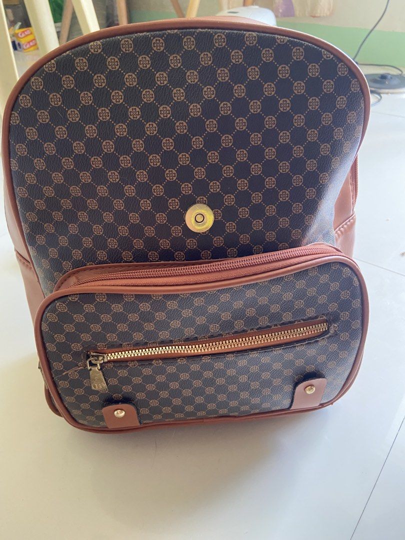 Brown Monogram Backpack with Faux Leather Trim (Category: Backpacks) located in Bangui. Submitted by loricam (Listing ID 1462974284, Image 2). Description: - Cute brown backpack with classic monogram print - Faux leather trim and straps - Front zip pocket - Spacious main compartment, fits several books - Gold-tone hardware - Great for school or everyday use.