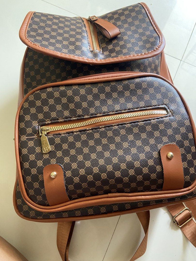 Brown Monogram Backpack with Faux Leather Trim (Category: Backpacks) located in Bangui. Submitted by loricam (Listing ID 1462974284, Image 1). Description: - Cute brown backpack with classic monogram print - Faux leather trim and straps - Front zip pocket - Spacious main compartment, fits several books - Gold-tone hardware - Great for school or everyday use.