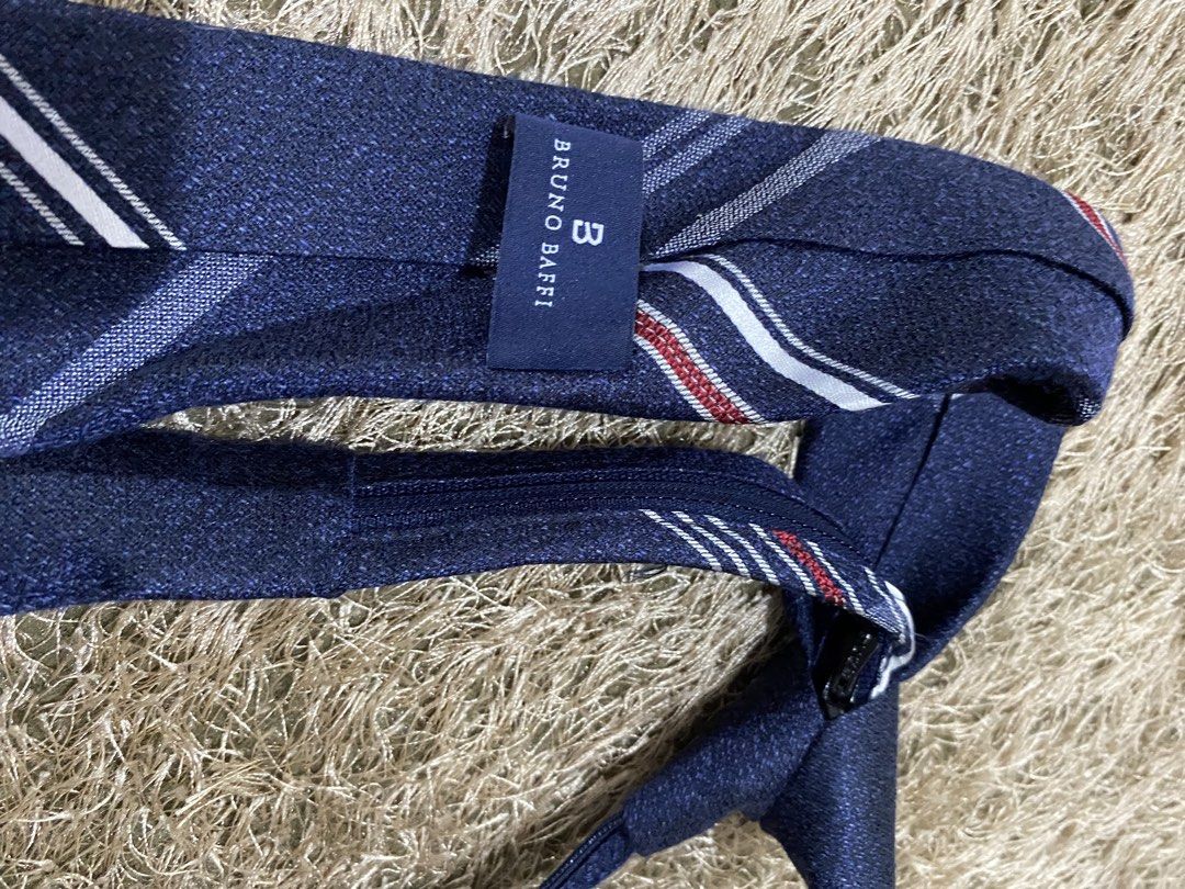 Bruno Baffi Navy Blue Plaid Tie (Category: Ties) located in Bulacan. Submitted by rich2545 (Listing ID 1462905572, Image 2). Description: - Brand: Bruno Baffi - Color: Navy blue - Pattern: Plaid with white and red stripes - Accent: Small metal emblem on the front - Style: Suitable for both formal and casual wear.