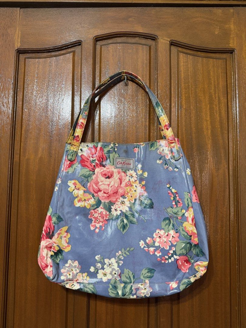 Cath Kidston Floral Tote Bag (Category: Tote Bags) located in Manila. Submitted by prelovedbylkt (Listing ID 1463031451, Image 1). Description: - Brand: Cath Kidston - Style: Floral Tote Bag - Color: Blue base with vibrant floral print - Interior: Pink polka dot lining with multiple pockets - Closure: Button at the top - Ideal for: Everyday use, travel bag - Issue: Stains on exterior .