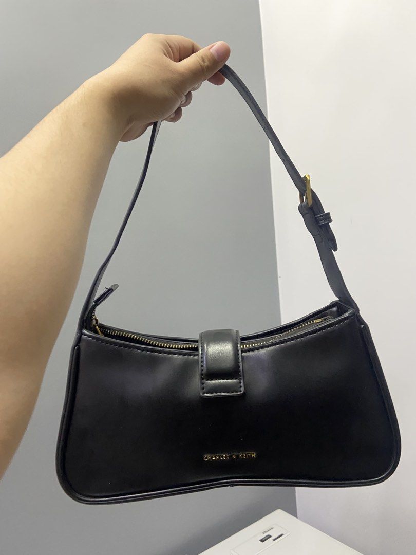 Charles & Keith Black Shoulder Bag with Gold Hardware (Category: Shoulder Bags) located in Cabanatuan. Submitted by kimmyyy12344 (Listing ID 1463047956, Image 2). Description: - Brand: Charles & Keith - Color: Black - Style: Classic Baguette Shoulder Bag - Features: Gold D-ring buckle detail on front flap - Closure: Zipper - Versatile: Ideal for everyday wear or evening outings - Design: Minimalist.