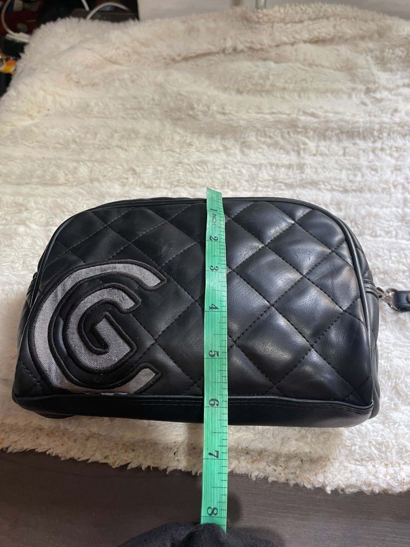 Cleveland Quilted Cosmetic Bag Pouch (Category: Purses & Pouches) located in Naawan. Submitted by twilly.apparel2 (Listing ID 1462950232, Image 3). Description: - Black quilted cosmetic bag from Cleveland - Features a large 'G' logo on the front - Secure zipper closure - Includes a convenient wrist strap - Dimensions: Approximately 9 inches long and 4 inches tall - Ideal for travel or everyday organization.