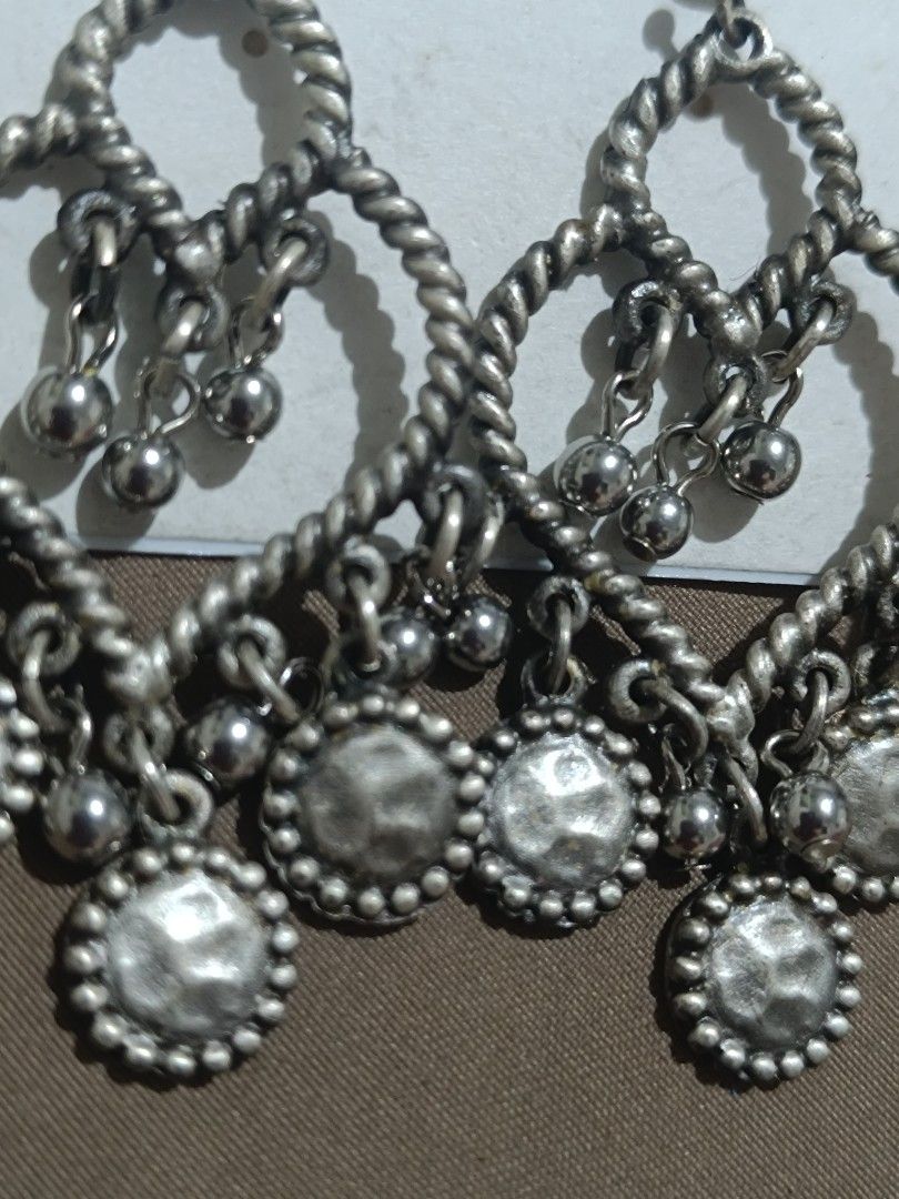 C.O. & Co. Silver Dangle Earrings with Charms (Category: Earrings) located in Bacolod City. Submitted by jewels.of.joy (Listing ID 1462998344, Image 3). Description: - Brand: C.O. & Co. - Material: Silver tone - Design: Twisted heart shape with multiple small dangling charms - Style: Cute, adds flair to any outfit - Occasion: Perfect for casual wear or dressing up.