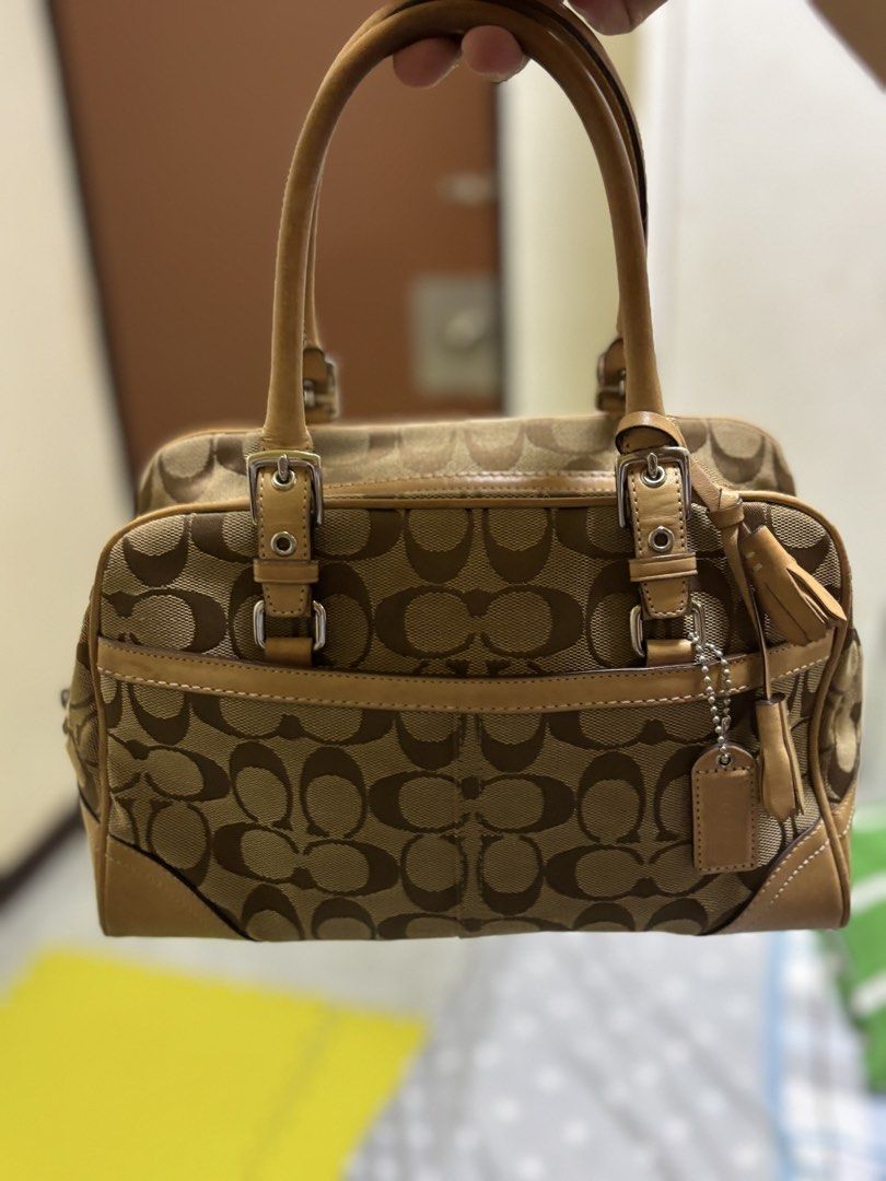 Coach Monogram Canvas Leather Trimmed Handbag (Category: Luxury Bags & Wallets) located in Silang. Submitted by lakasthrift1577 (Listing ID 1463021949, Image 1). Description: - Classic Coach monogram canvas handbag - Tan leather trim and handles - Secure top zipper closure - Charming small tassel detail on the side - Interior tag with serial number N° B06W-8K05 - A timeless and versatile piece No issue .
