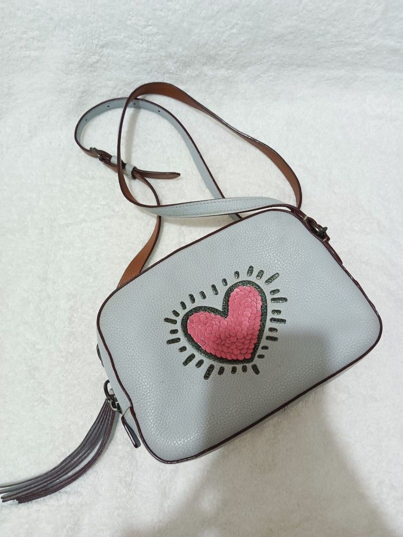 COACH x KEITH HARING SEQUINS HEART CAMERA BAG (Category: Luxury Bags & Wallets) located in Manila. Submitted by sabrinacalin (Listing ID 1463076900, Image 1). Description: ✨ ✨ 💗 Style No. 28661 ✨ Beautiful sequins heart design 👜 Compact camera bag — perfect for everyday use 📏 Dimensions: L 20cm × W 6.5cm × H 15cm A cute and eye-catching piece featuring the iconic Keith Haring design! Perfect for adding a fun touch to any outfit. 💕✨ 📩 PM for 