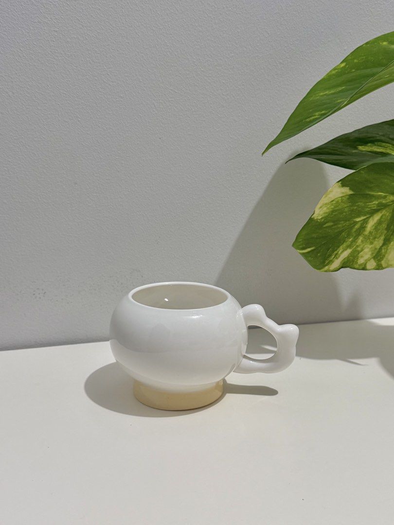 Cute White Round Mug with Unique Handle (Category: Coffee & Tea Tableware) located in Makati City. Submitted by ariannelaz54133 (Listing ID 1462927665, Image 1). Description: - White ceramic mug with a rounded body - Unique, bulbous handle for a comfortable grip - Light yellow accent on the base adds a pop of color - Ideal for enjoying your favorite coffee or tea - A fun and stylish addition to your kitchenware - Makes a thoughtful gift for frien