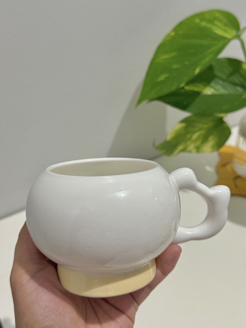 Cute White Round Mug with Unique Handle (Category: Coffee & Tea Tableware) located in Makati City. Submitted by ariannelaz54133 (Listing ID 1462927665, Image 2). Description: - White ceramic mug with a rounded body - Unique, bulbous handle for a comfortable grip - Light yellow accent on the base adds a pop of color - Ideal for enjoying your favorite coffee or tea - A fun and stylish addition to your kitchenware - Makes a thoughtful gift for frien