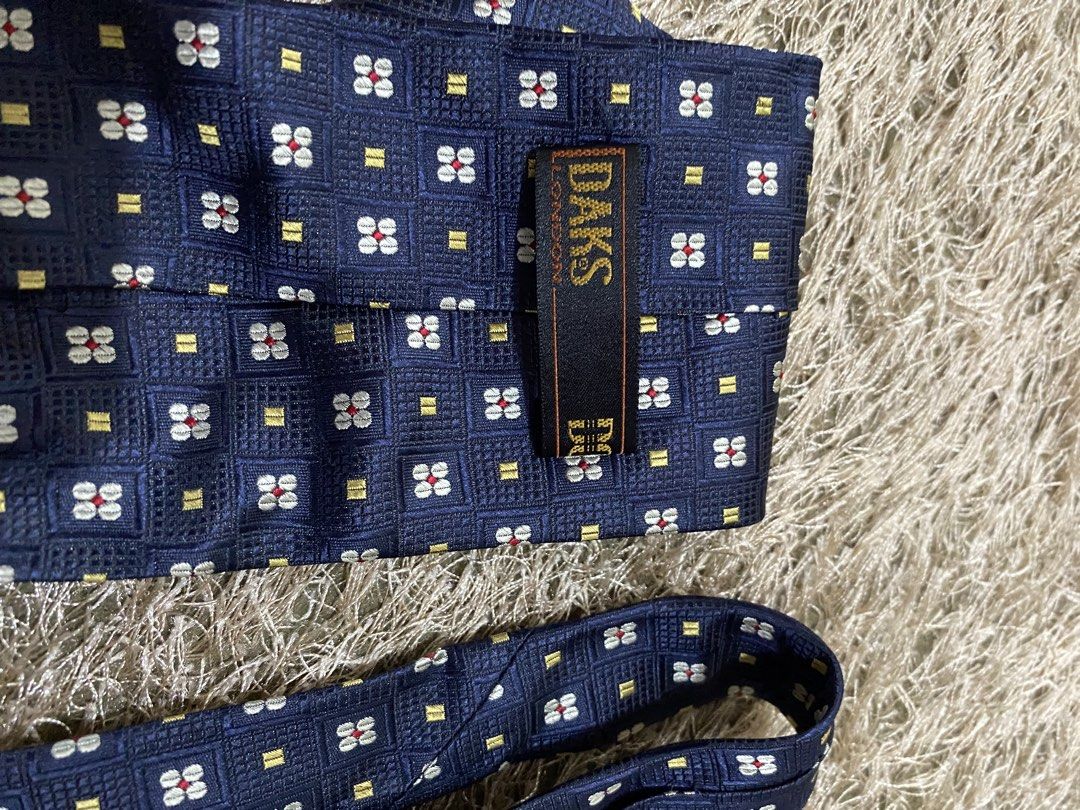 Daks London Silk Tie - Navy Blue Geometric Pattern (Category: Ties) located in Bulacan. Submitted by rich2545 (Listing ID 1462905648, Image 2). Description: - Classic navy blue silk tie from Daks London. - Features a repeating geometric pattern. - Accents of red, white, and yellow. - Ideal for formal or business occasions. - Adds sophistication to any outfit..