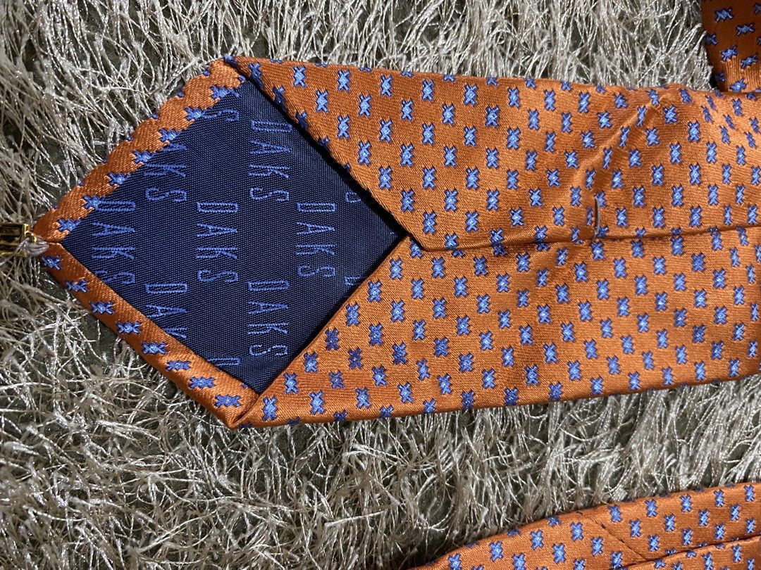 DAKS Silk Tie - Orange with Blue Pattern (Category: Ties) located in Bulacan. Submitted by rich2545 (Listing ID 1462902940, Image 2). Description: - Elegant orange silk tie - Features a small, stylish blue pattern - Authentic DAKS logo on the back - Versatile accessory to enhance any outfit - A must-have addition to your collection.