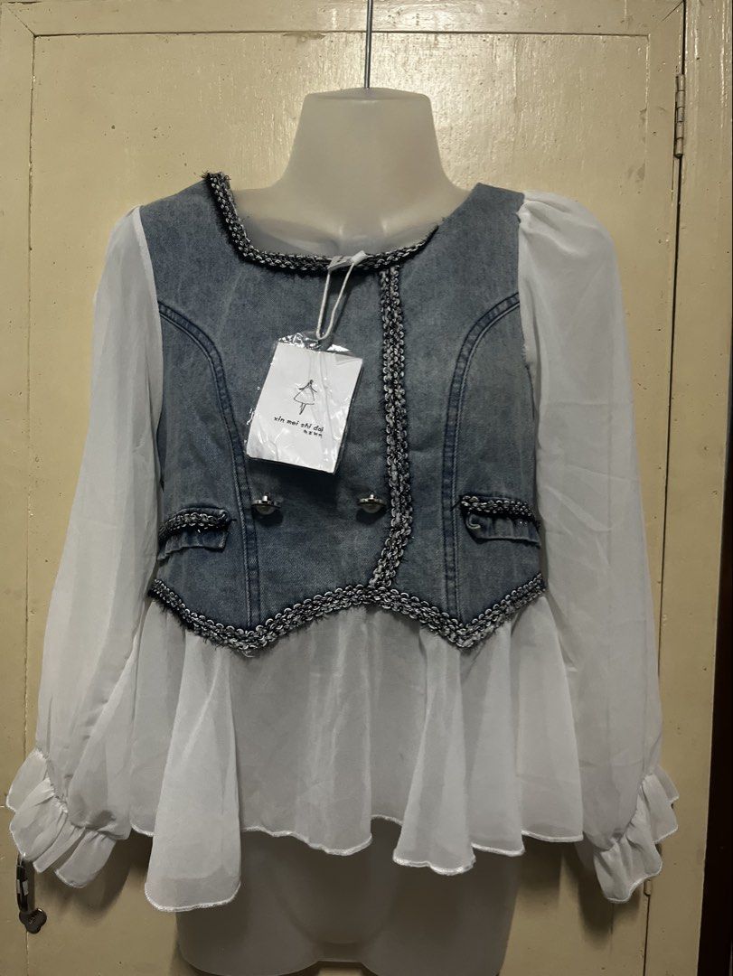 Denim Vest White Sheer Sleeve Top (Category: Sleeveless) located in Tabuk. Submitted by zenwolf-1867 (Listing ID 1463052859, Image 2). Description: - Brand new denim vest top with tags attached - Features sheer puff sleeves - Decorative trim and buttons for added style - Convenient back zipper closure - Versatile for layering or wearing solo.