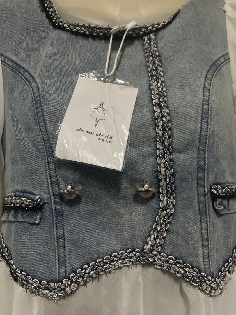 Denim Vest White Sheer Sleeve Top (Category: Sleeveless) located in Tabuk. Submitted by zenwolf-1867 (Listing ID 1463052859, Image 3). Description: - Brand new denim vest top with tags attached - Features sheer puff sleeves - Decorative trim and buttons for added style - Convenient back zipper closure - Versatile for layering or wearing solo.
