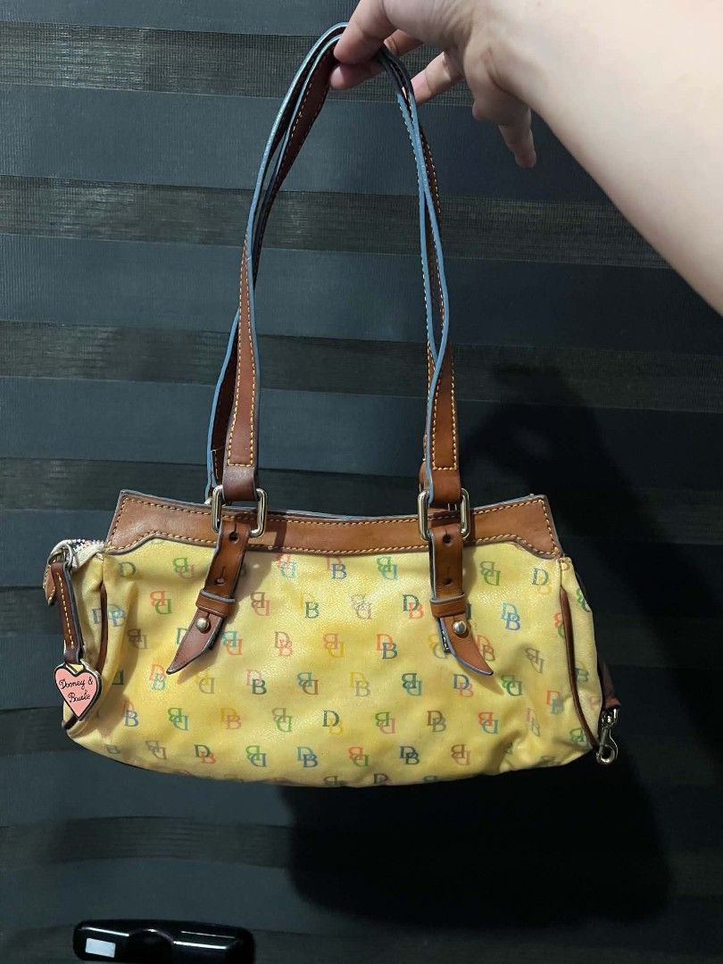 Dooney & Bourke Vintage Tasche (Category: Luxury Bags & Wallets) located in Quezon City. Submitted by all_for_love (Listing ID 1463100531, Image 3). Description: - Cute Dooney & Bourke satchel bag - Classic all-weather leather with multi-color 'DB' monogram - Brown leather trim and handles - Includes signature heart charm - Spacious interior for essentials - Fun and colorful addition to any outfit Dm me for sure buyer .