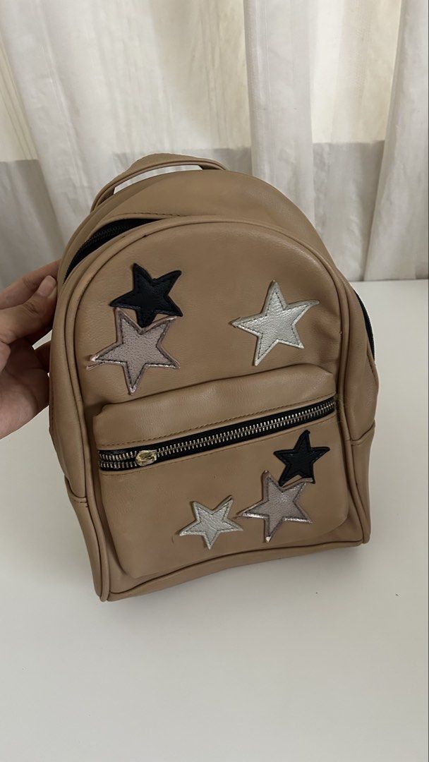 Fioni Leather Bag (Payless) (Category: Backpacks) located in Cavite. Submitted by yamyam. (Listing ID 1462914780, Image 1). Description: - Cute tan mini backpack - Black and silver star appliques on the front - Polka dot lining inside the main compartment - Zipper closure - Small top handle and adjustable shoulder straps - Ideal for everyday use or travel.