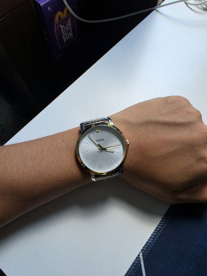Fossil Watch Two-Tone Stainless Steel (Category: Women's Watches) located in Imus. Submitted by cslek020 (Listing ID 1461624801, Image 2). Description: - Fossil watch with a classic silver and gold two-tone stainless steel band. - Clean white watch face with simple hour markers. - Features a subtle diamond accent at the 12 o'clock position. - Versatile design suitable for everyday wear or dressing up. - Authentic Fossil branding visible on the wa
