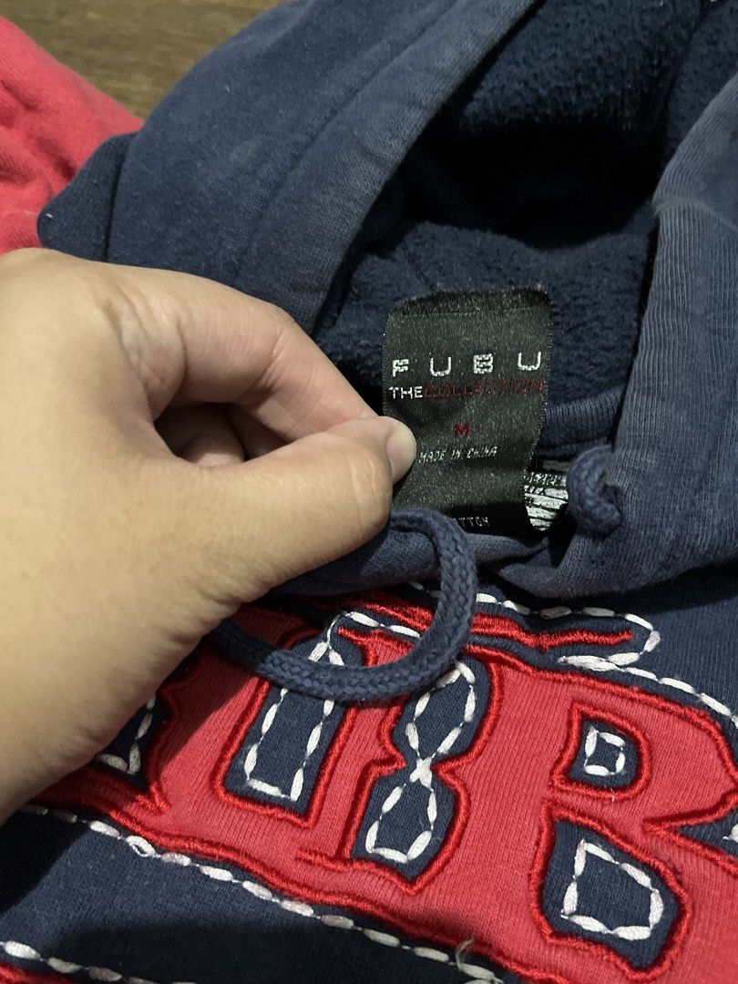 FUBU The Collection Hoodie (Category: Hoodies) located in Manila. Submitted by mcqueendumps (Listing ID 1462990145, Image 2). Description: - Classic FUBU hoodie - Navy blue body with red sleeves - Prominent FUBU logo across the chest - Convenient kangaroo pocket - Adjustable drawstring hood - Size Medium (M) - Ideal for everyday casual wear.