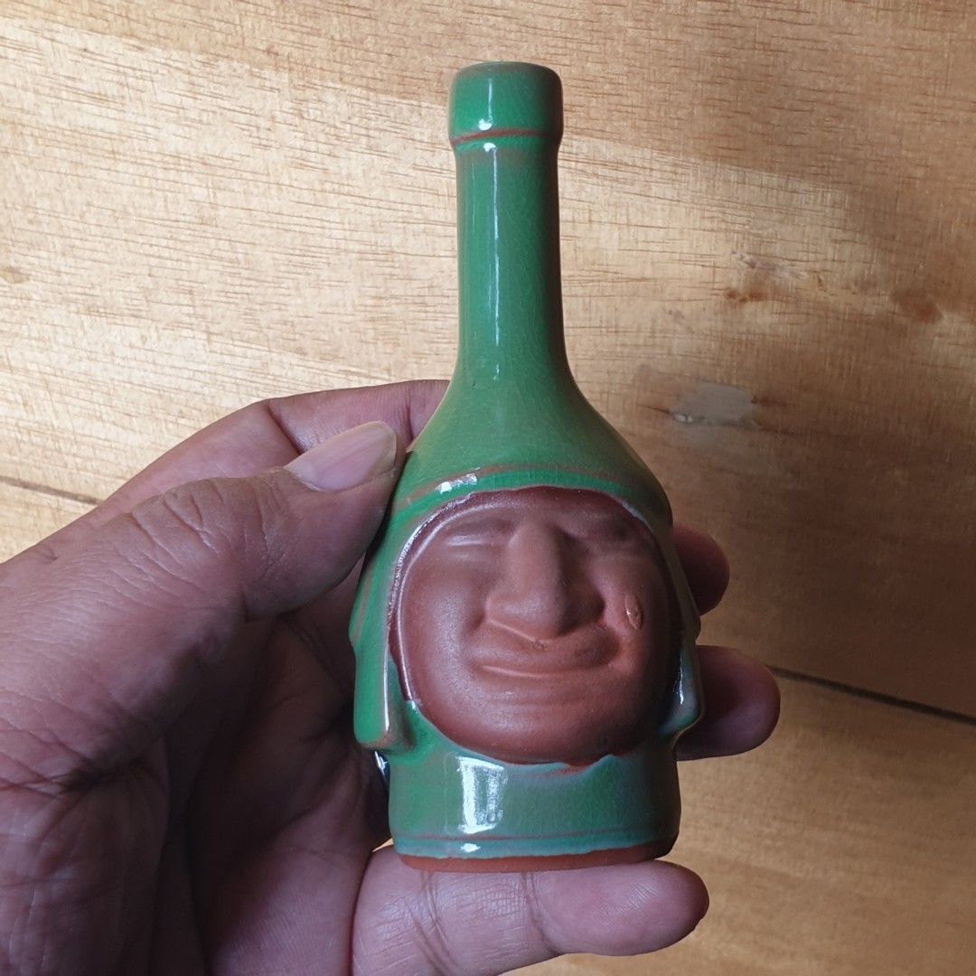 Green Ceramic Bottle with Face Design (Category: Vases & Decorative Bowls) located in Iligan City. Submitted by sariranaw (Listing ID 1463003131, Image 1). Description: - Unique green ceramic - Bottle shape with a carved face - Subtle color variations in glaze - Opening located at the neck - Unglazed terracotta base - Perfect for collectors of quirky items.
