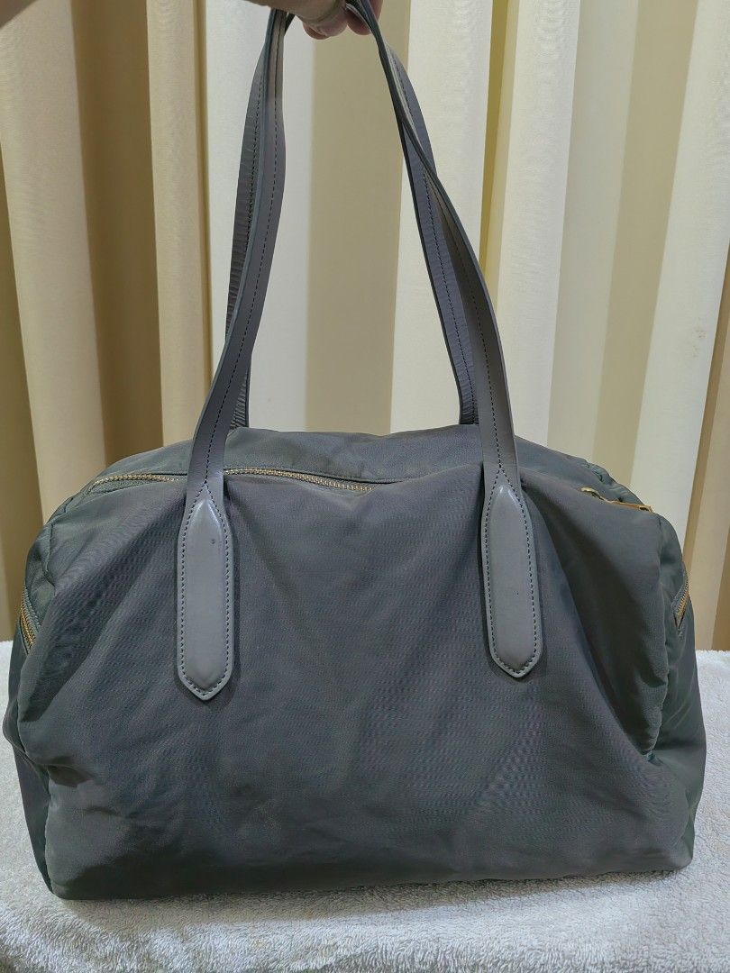 Grey Nylon Leather Tote Bag (Category: Shoulder Bags) located in Makati City. Submitted by prelovedtreatedwithlove (Listing ID 1463003970, Image 2). Description: - Grey tote bag - Material: Nylon with leather trim - Hardware: Gold details - Closure: Zipper - Interior: Spacious main compartment with one zippered pocket - Perfect for: Everyday use or travel -Maganda ang leather quality. Walang rubs - Issue : last pic ung brand nawala. A-146.
